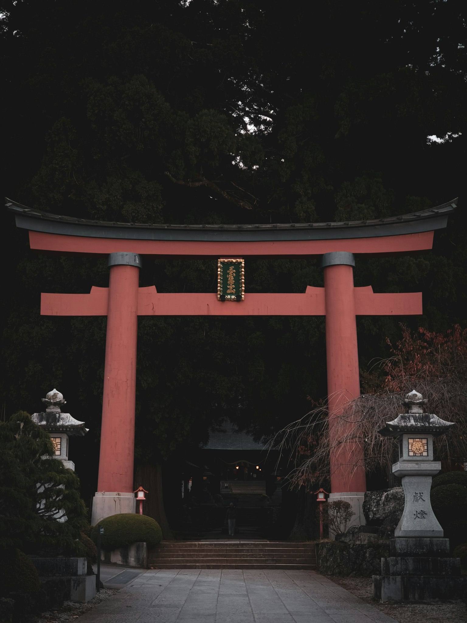 Eingang eines Schreins mit einem roten Torii und Laternen