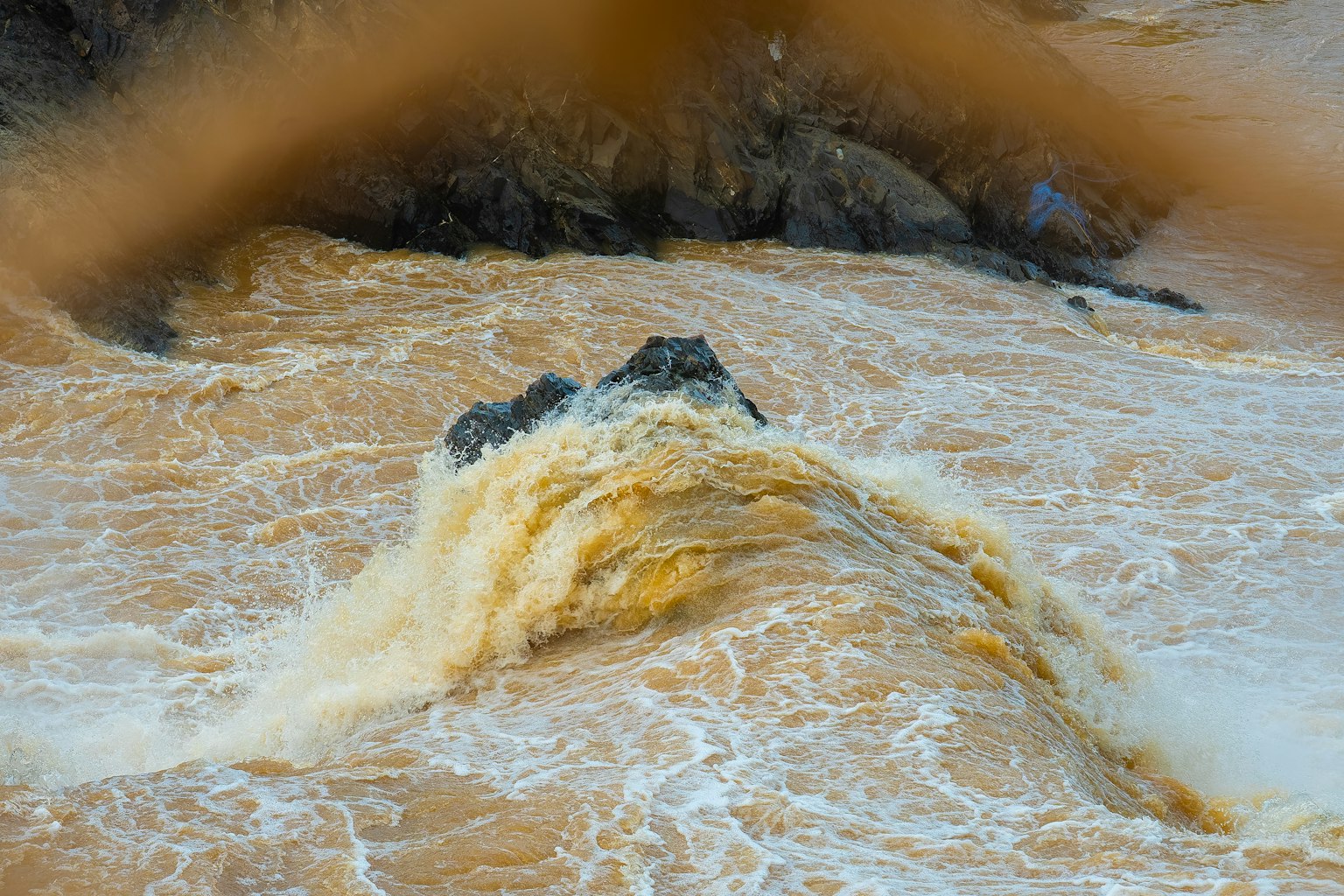 Flusso d'acqua impetuoso su una roccia con onde schiumose
