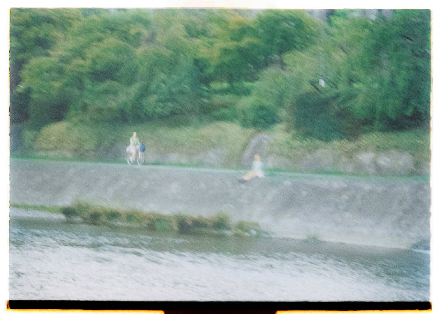 Scene with people near a river and green trees