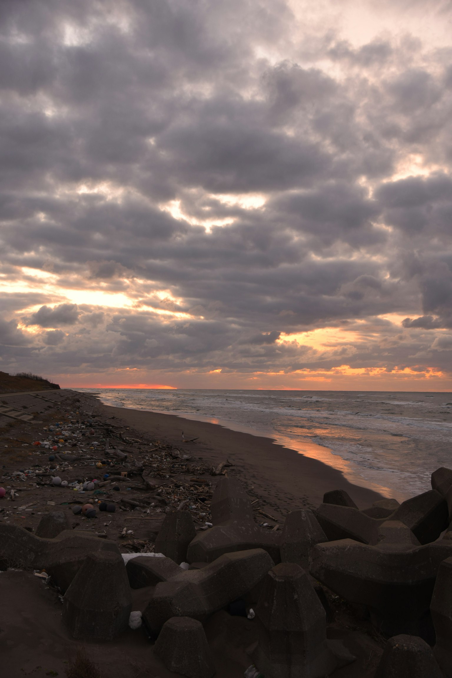 Pemandangan pantai saat matahari terbenam dengan awan luas dan ombak lembut