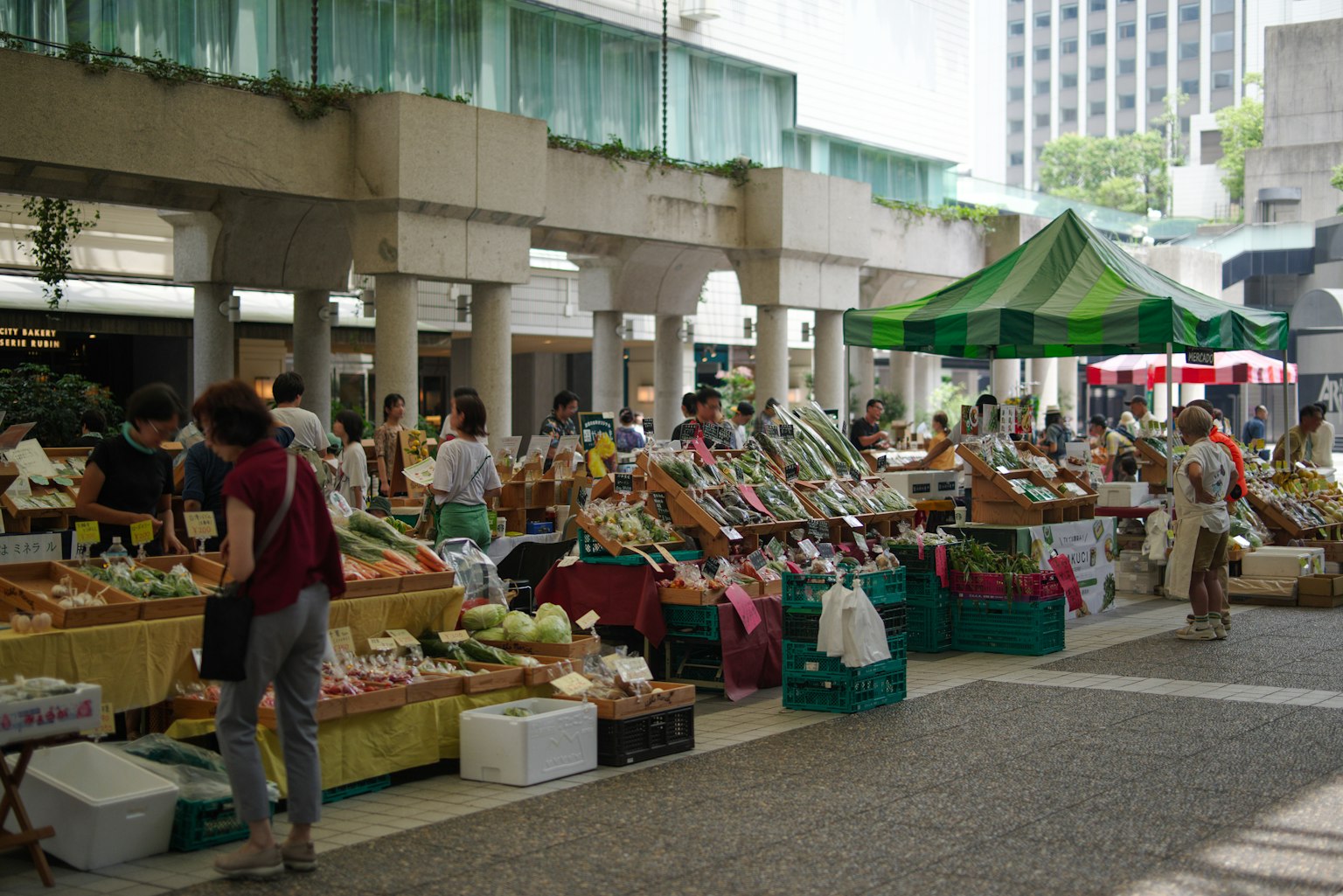 Mercato all'aperto con verdure e frutta fresca e persone che fanno la spesa