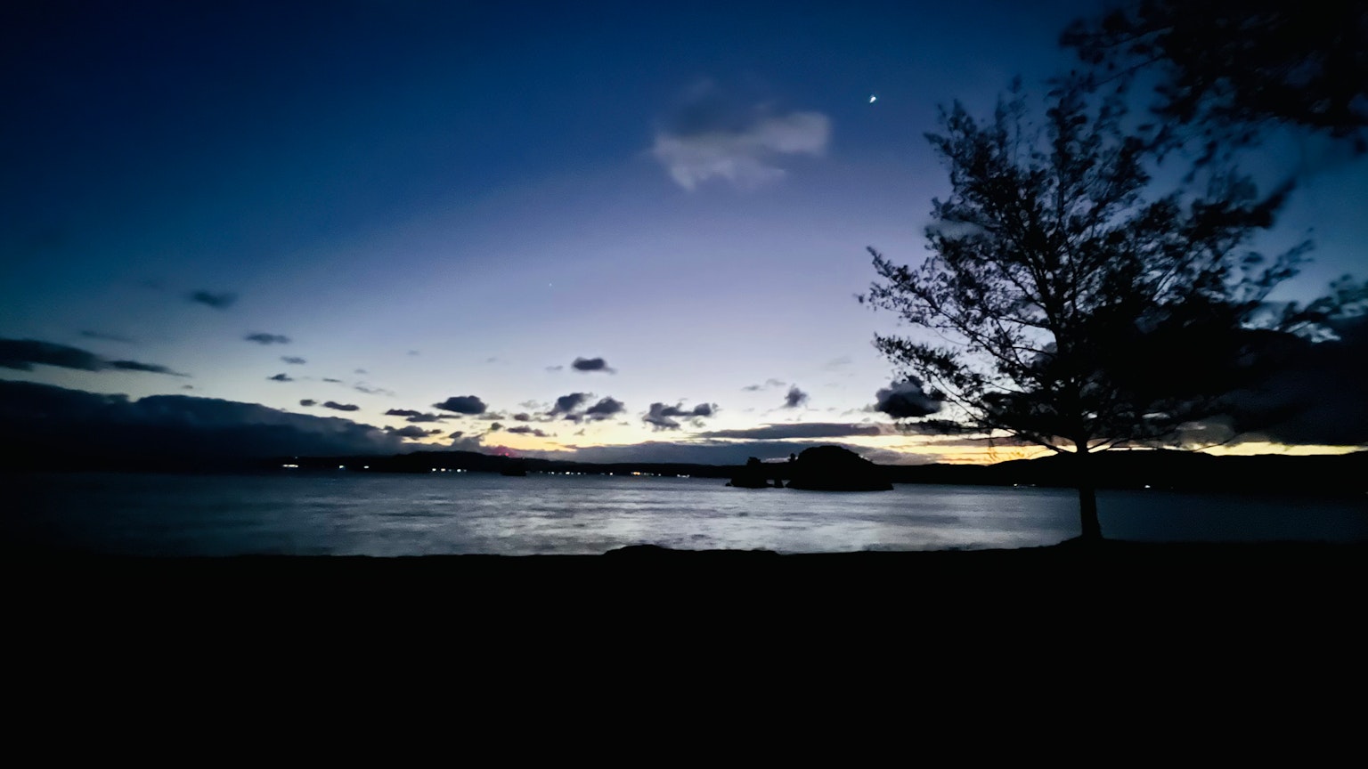 Vista panoramica del lago al crepuscolo con alberi in silhouette
