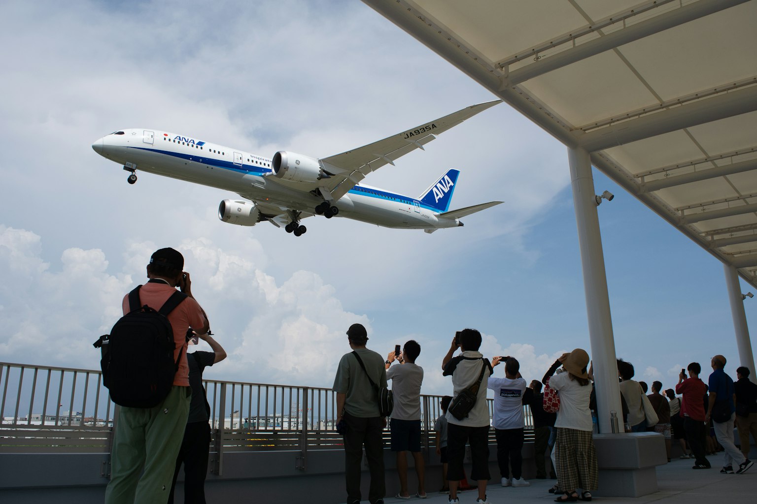 Espectadores en una plataforma de observación del aeropuerto viendo aterrizar un avión