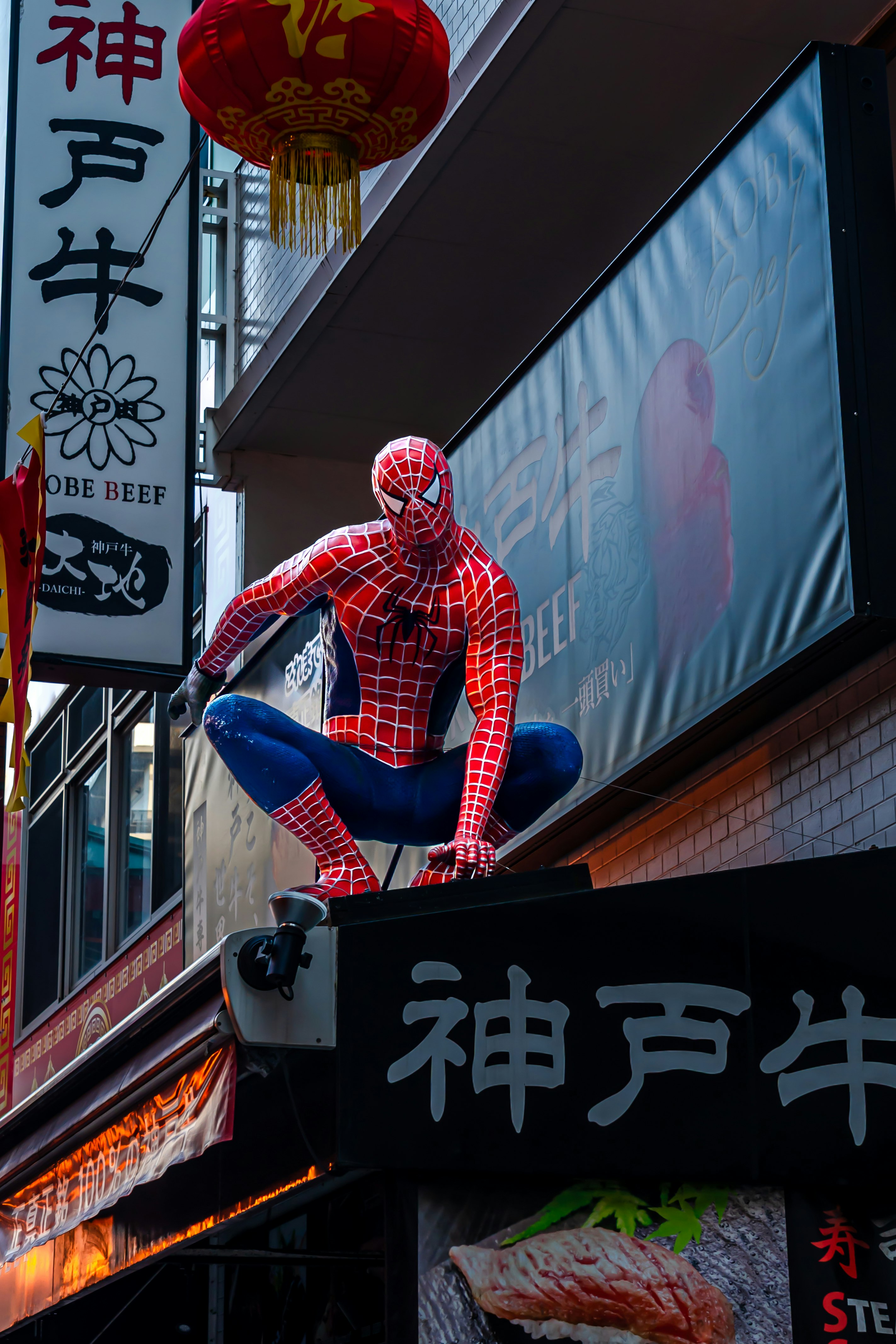 Enseigne Spider-Man et lanternes devant une boutique dans une ruelle de Kobe