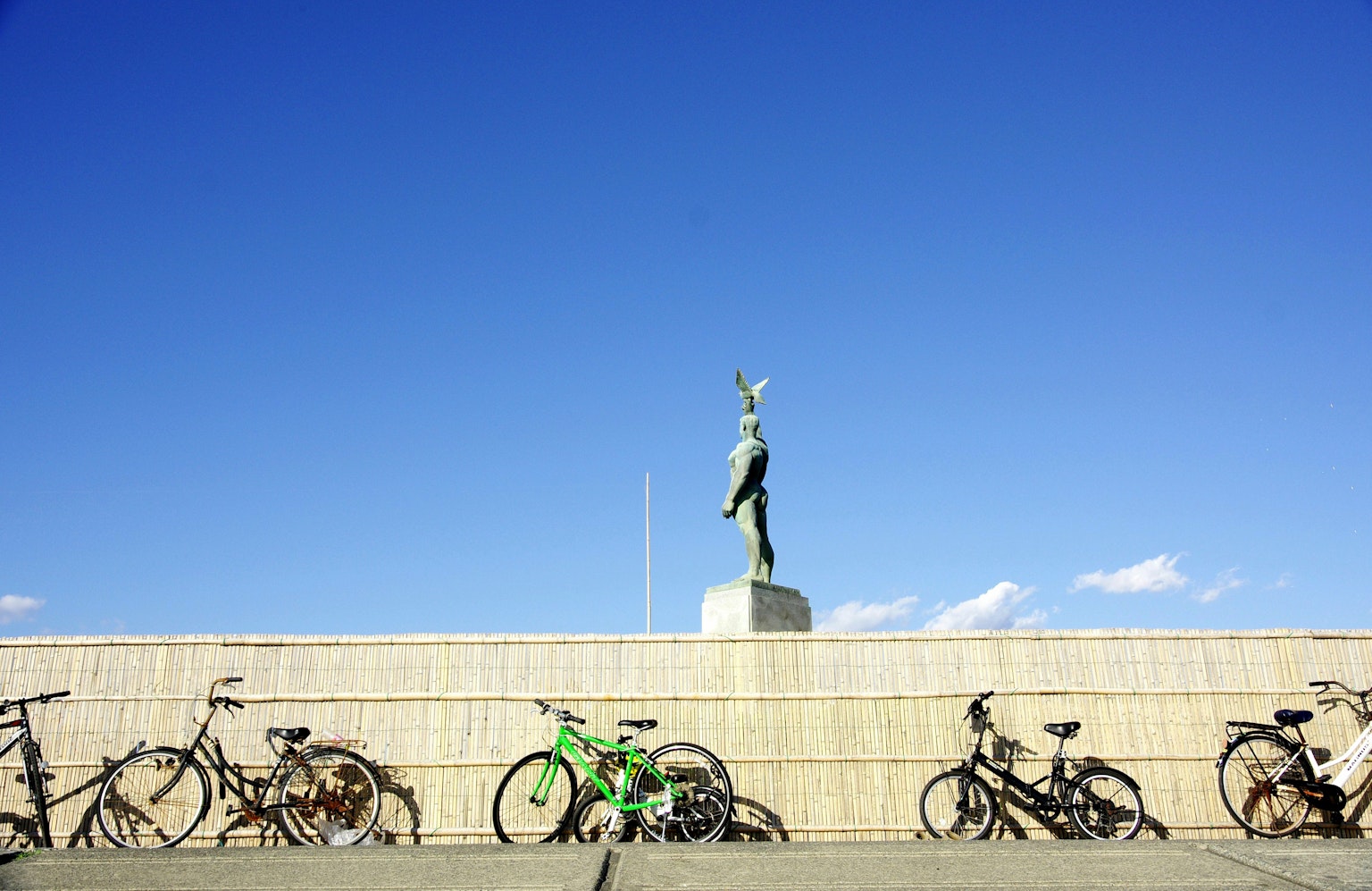 Statua che si erge sotto un cielo blu chiaro con biciclette in primo piano