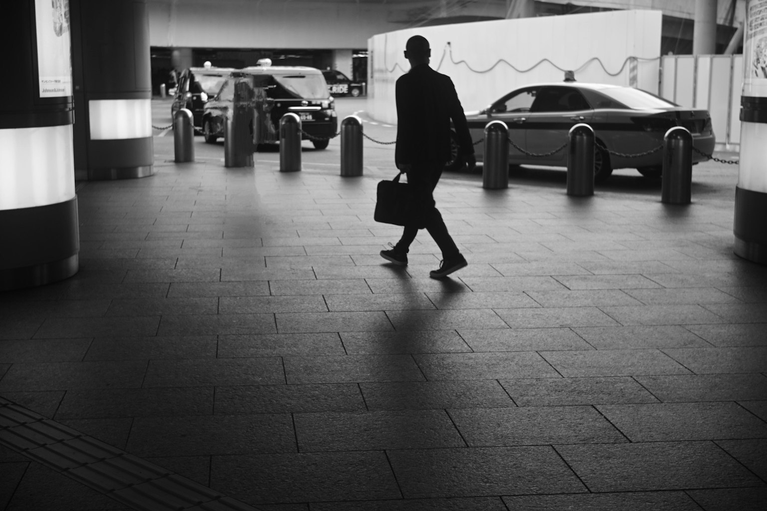 Silhouette di un uomo d'affari che cammina con una valigetta in un contesto urbano in bianco e nero