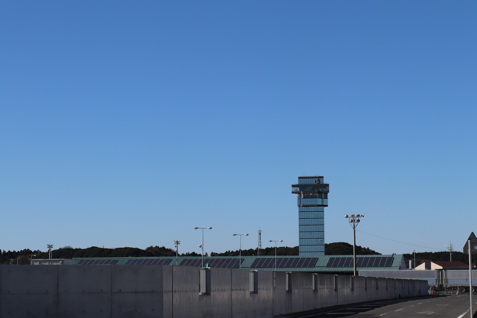 Airport control tower and fence under a clear blue sky