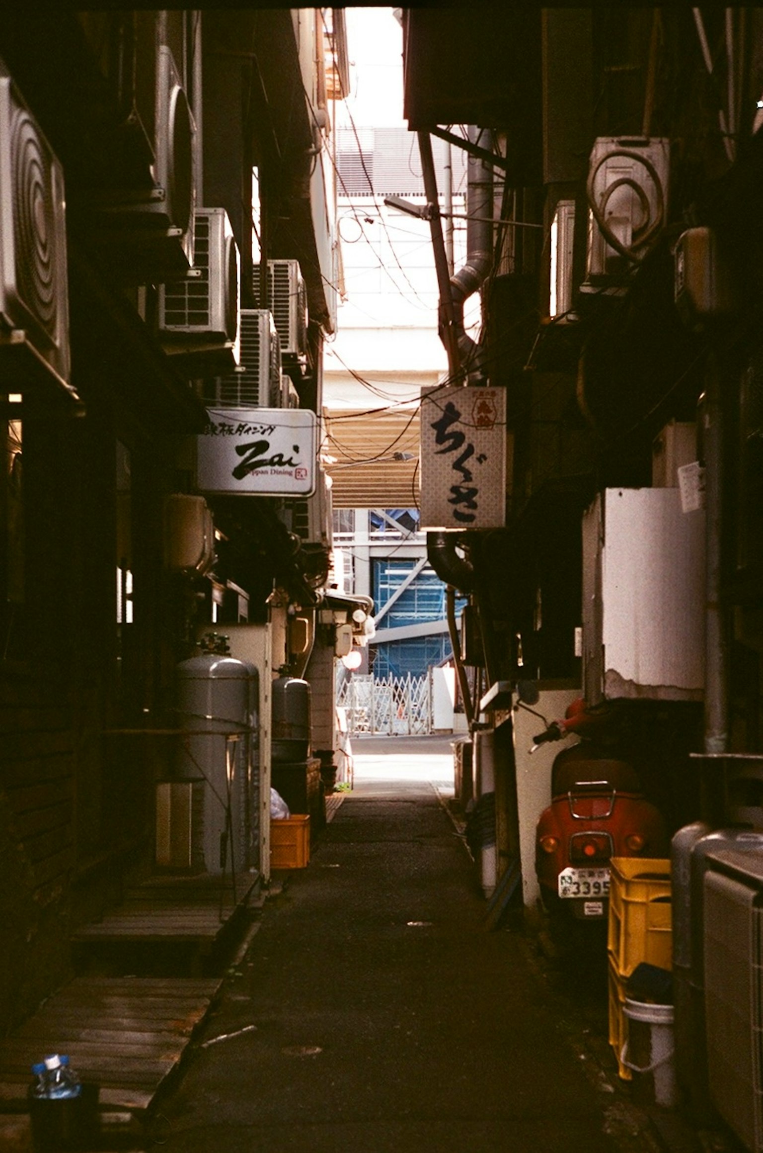 狹窄的巷子裡有餐館招牌和空調外機