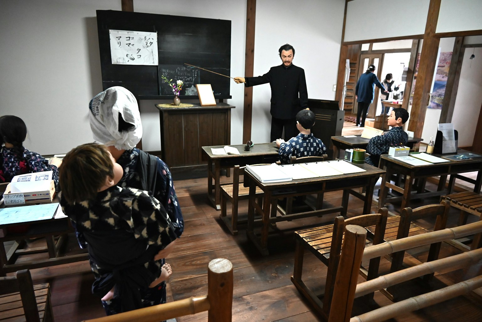 Scène de classe avec un enseignant pointant un tableau noir des élèves assis aux bureaux