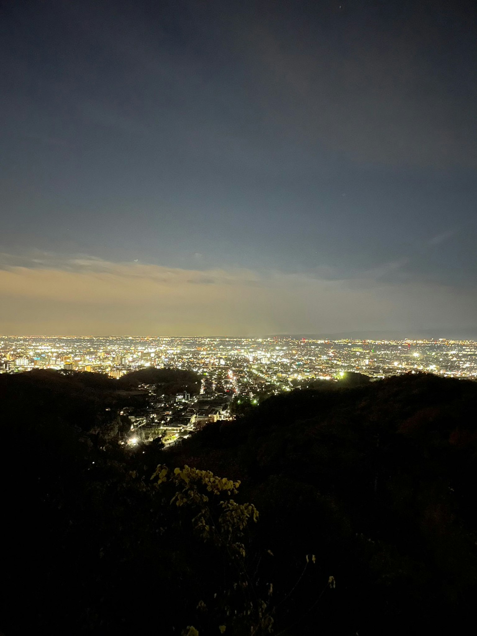 Ciudad iluminada por la noche con silueta de montaña