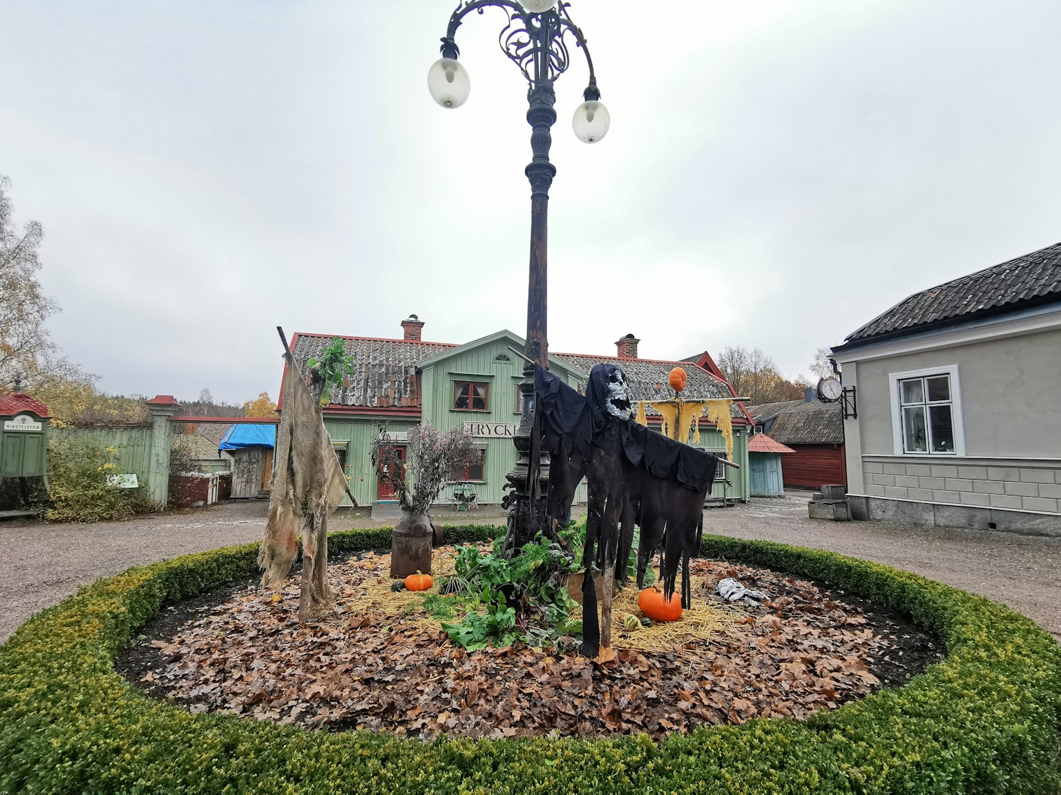 Caballo decorativo negro y farola en un parque rodeado de casas y camino
