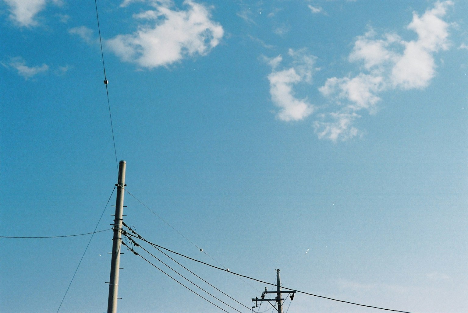 Strommasten und Drähte vor einem klaren blauen Himmel
