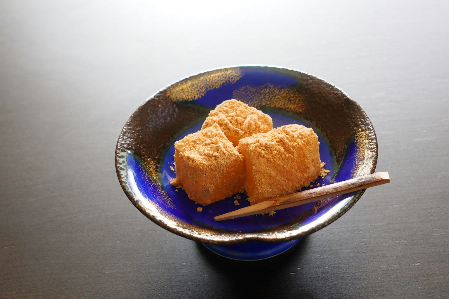 Tre dessert cremosi su un piatto blu con bacchette