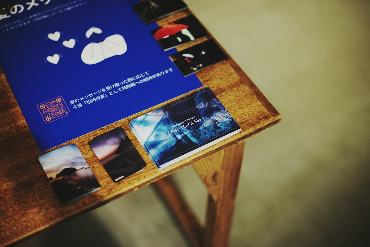 โต๊ะไม้ที่มีโปสเตอร์สีน้ำเงินที่มีการออกแบบเมฆและภาพถ่ายหลายภาพจัดเรียงรอบๆ