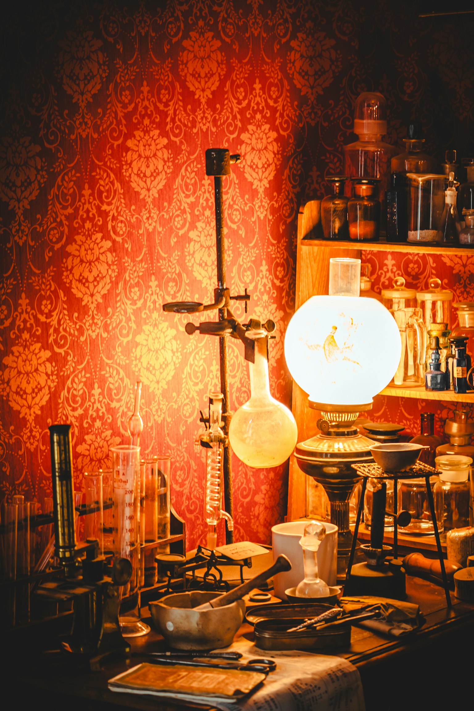 Koleksi peralatan ilmiah vintage dan lampu di latar belakang kertas dinding merah