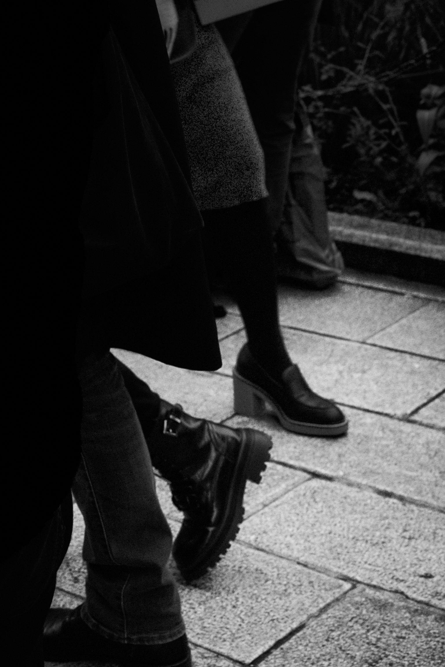 Imagen en blanco y negro de los pies de personas que llevan zapatos y botas negras
