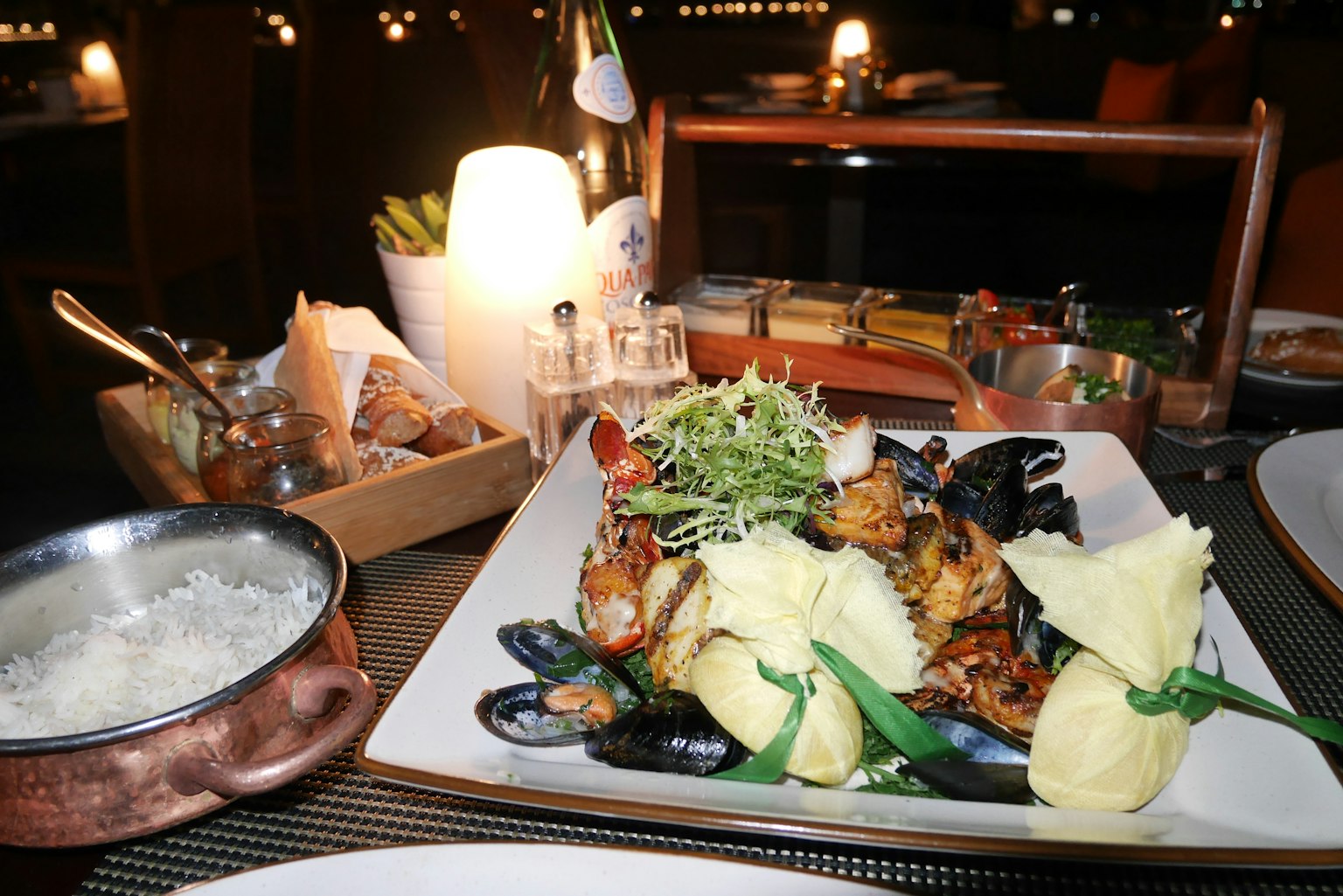 A seafood platter featuring mussels, white rice, salad, and rich desserts on a dining table
