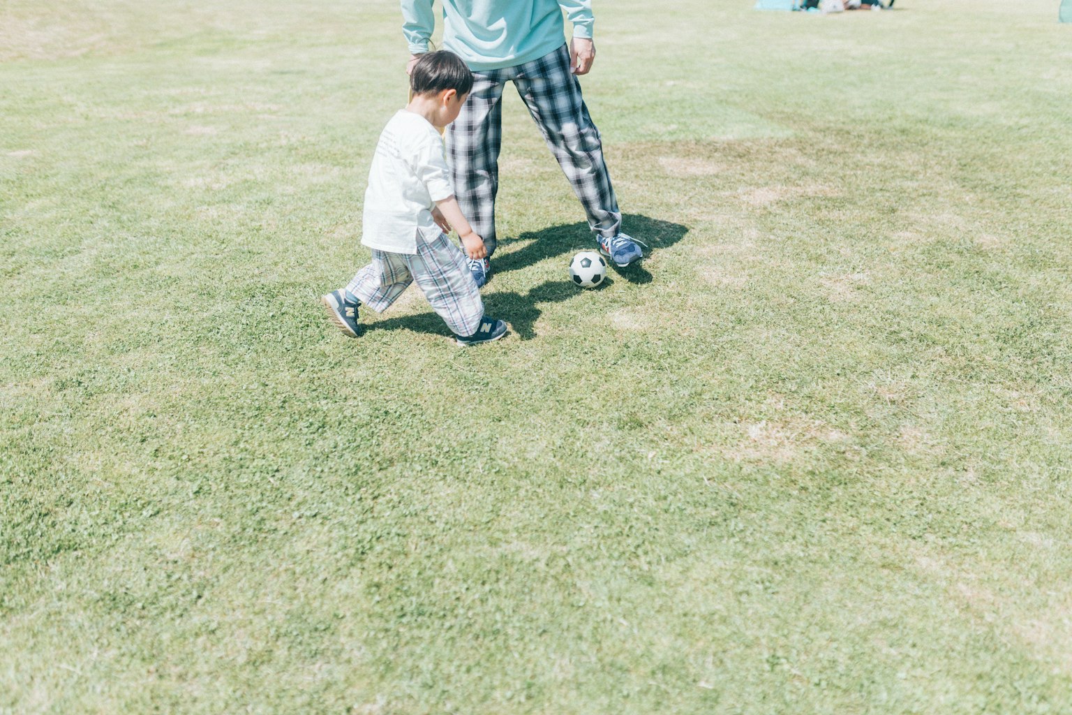 Un bambino che gioca a calcio con un adulto in un parco