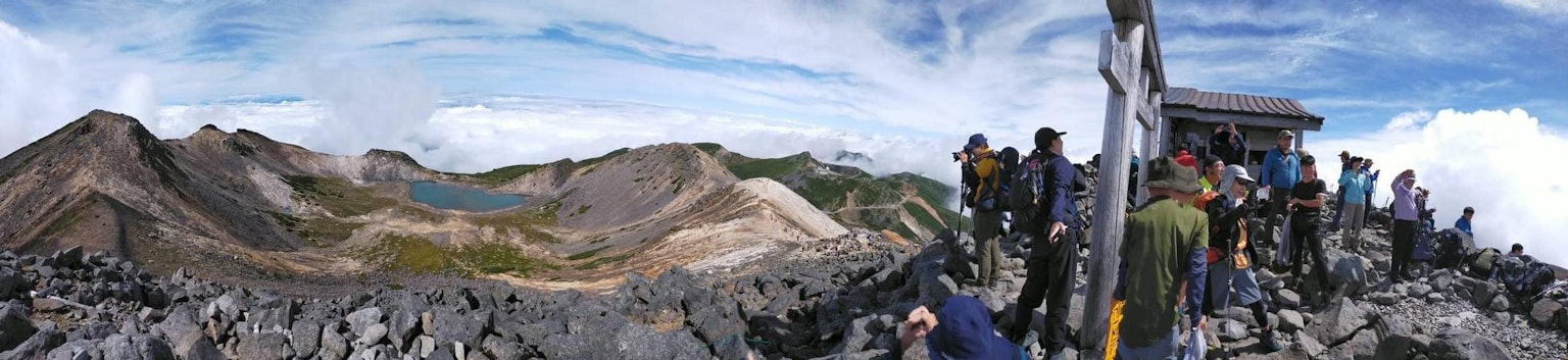 山顶上站着的人们的全景照片 展示了广阔的风景和岩石地形