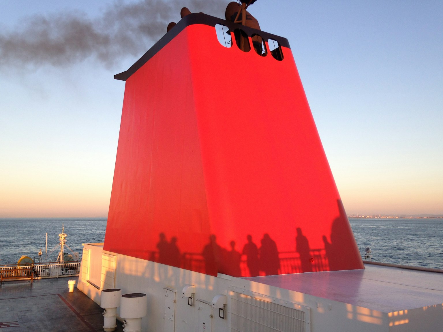 Ciminiera rossa di nave al tramonto con ombre