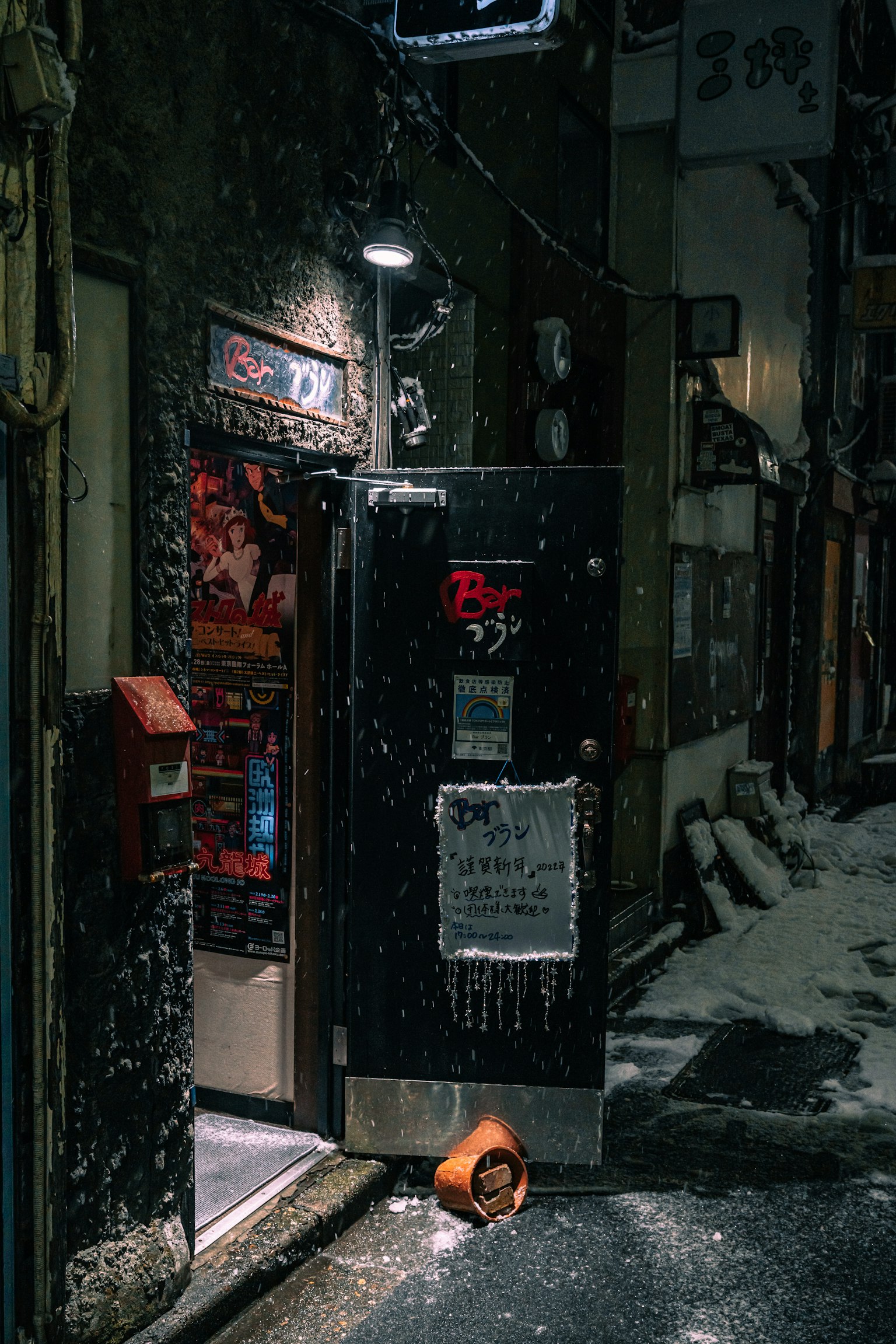 Pintu toko kecil di malam bersalju dengan kotak pos merah