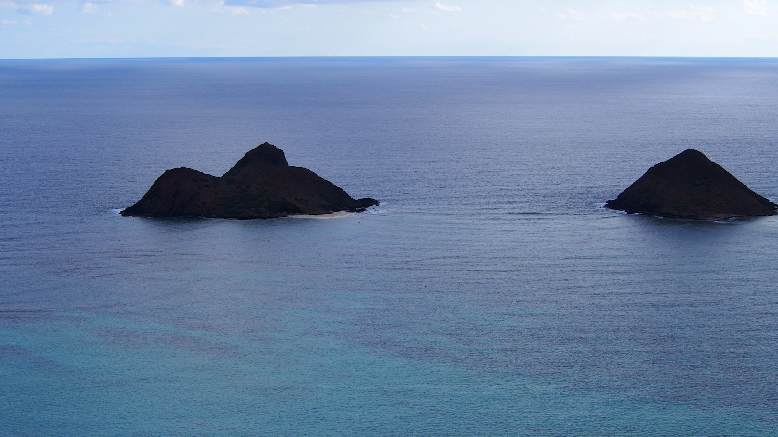 Two small islands floating in a blue sea and sky