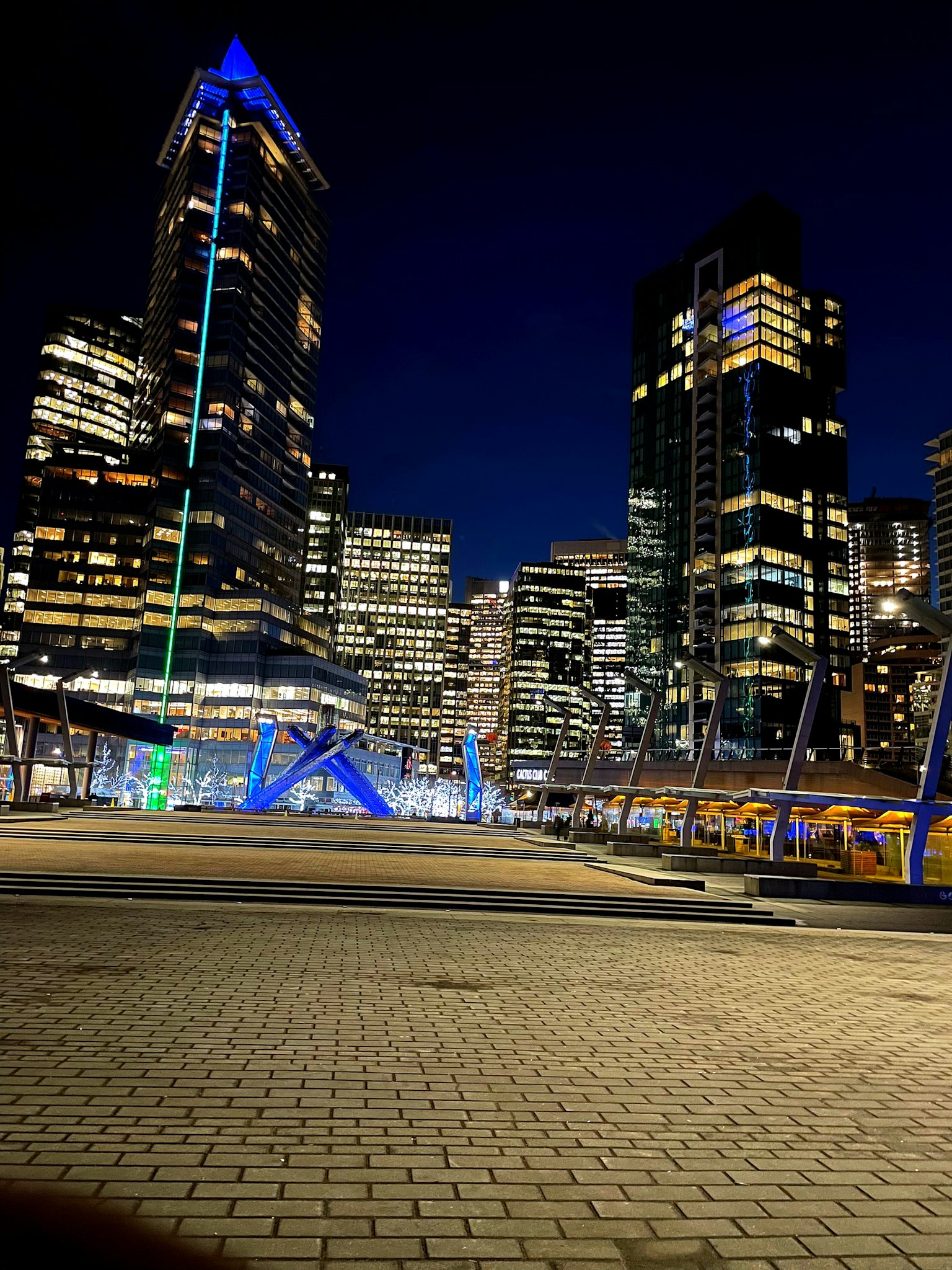 Paesaggio urbano notturno con grattacieli e illuminazione blu nella piazza