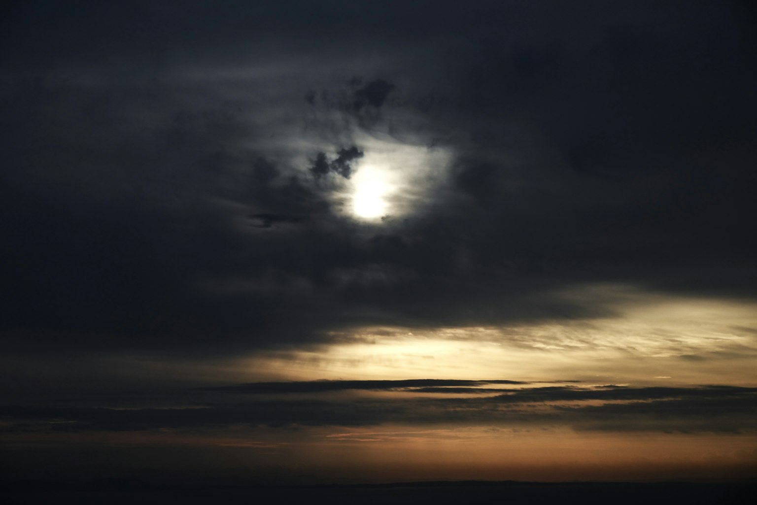 Sun shining through dark clouds in the sky