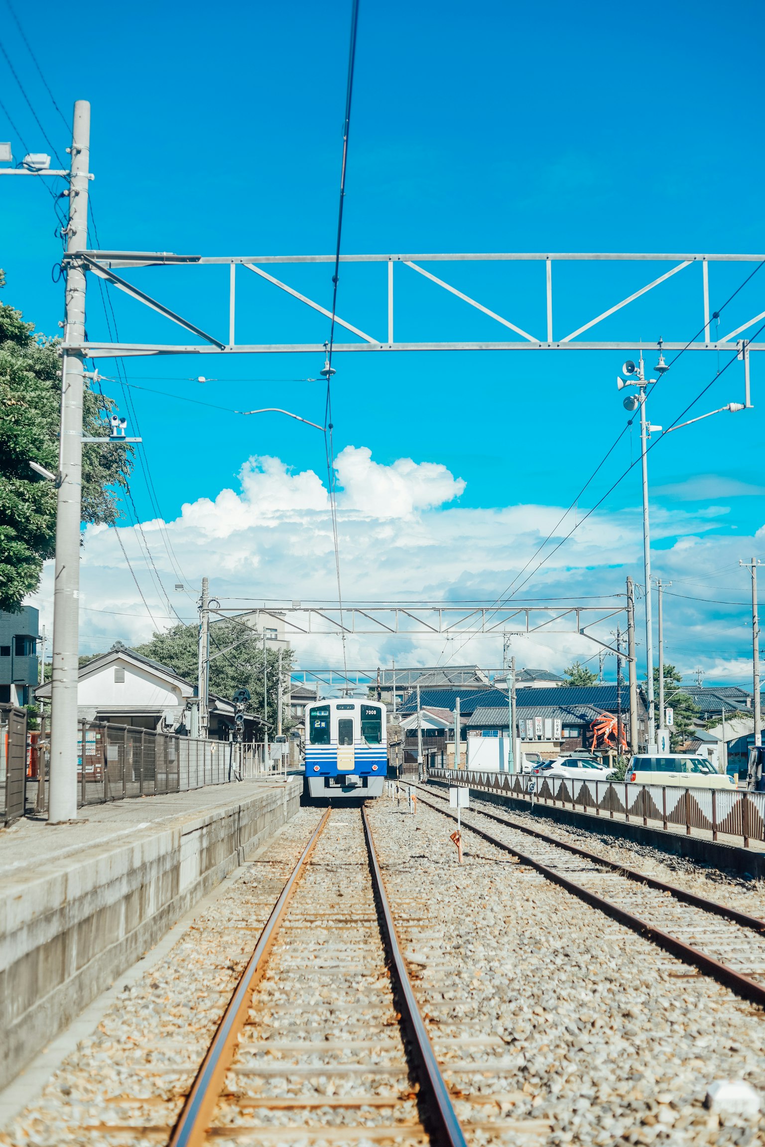 Escena de estación de tren con un tren bajo un cielo azul claro