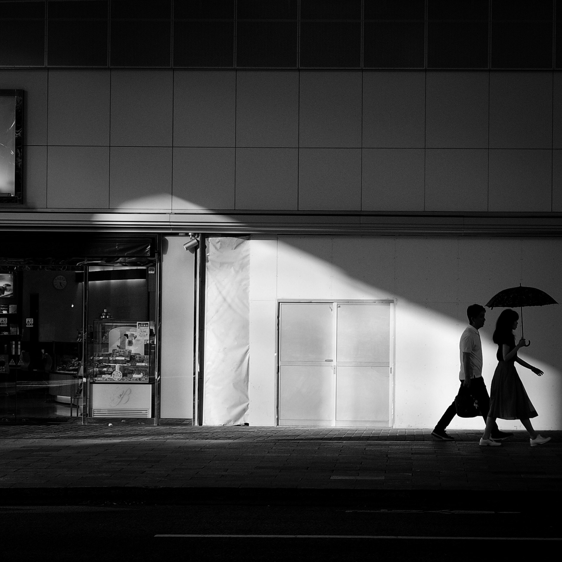 モノクロの路地を歩くふたりのシルエット