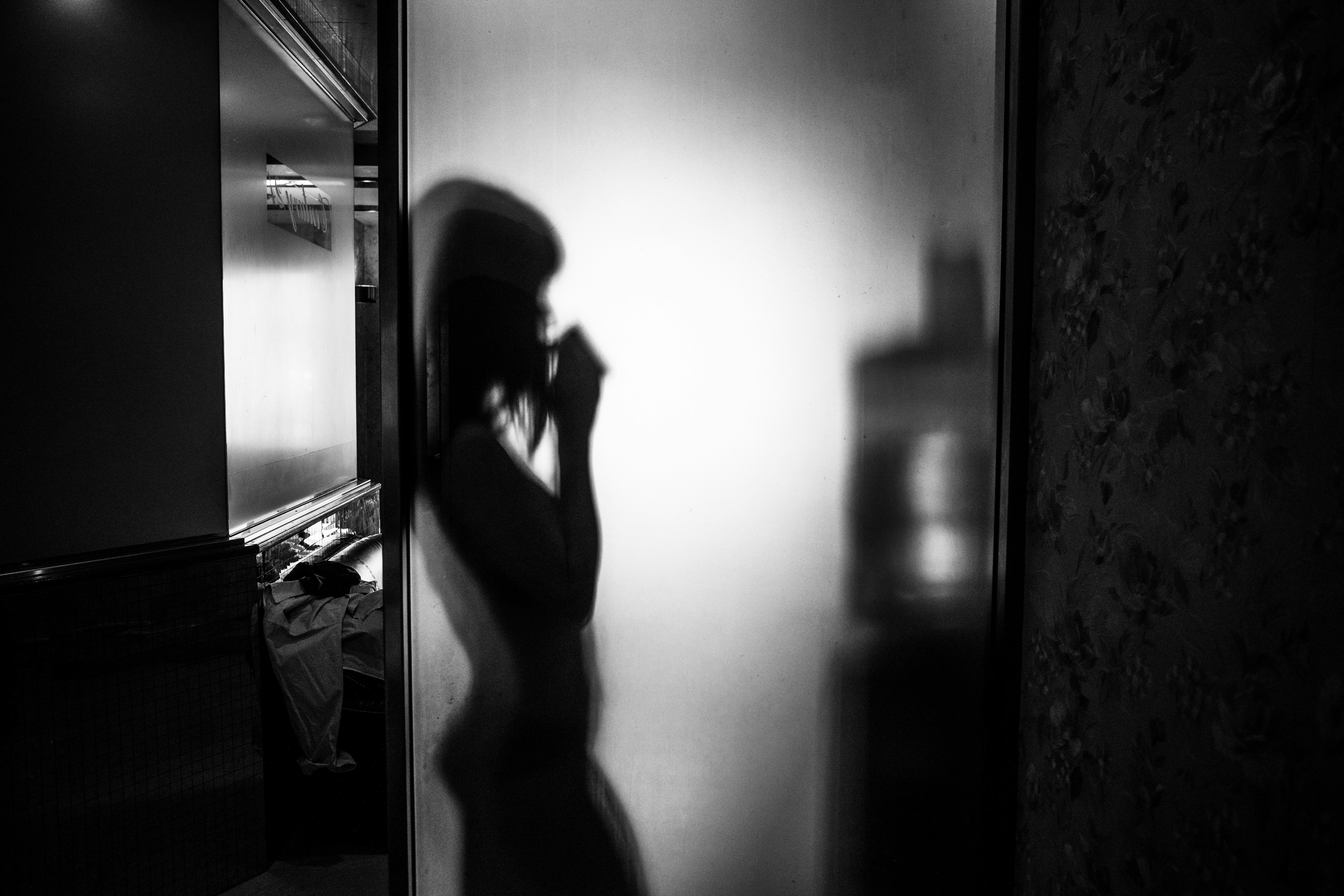 문틈으로 새어 들어오는 빛 속에 선 인물 실루엣