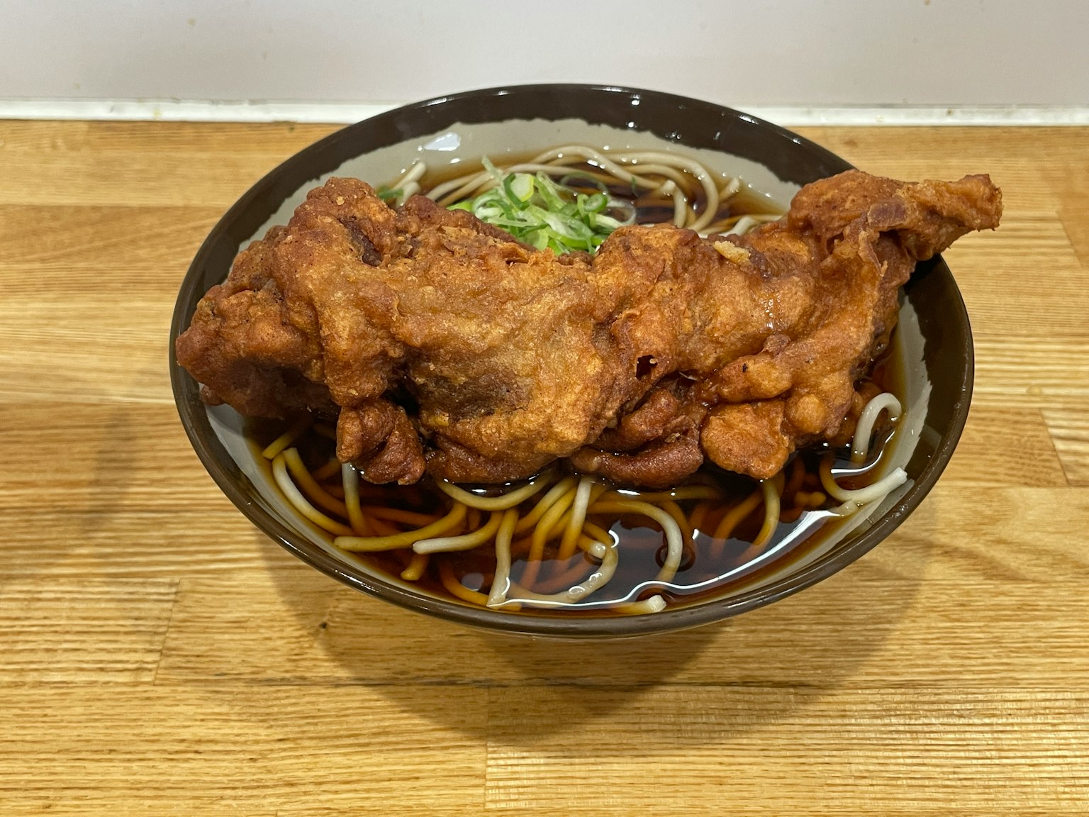 Tazón de fideos soba con pollo frito grande encima