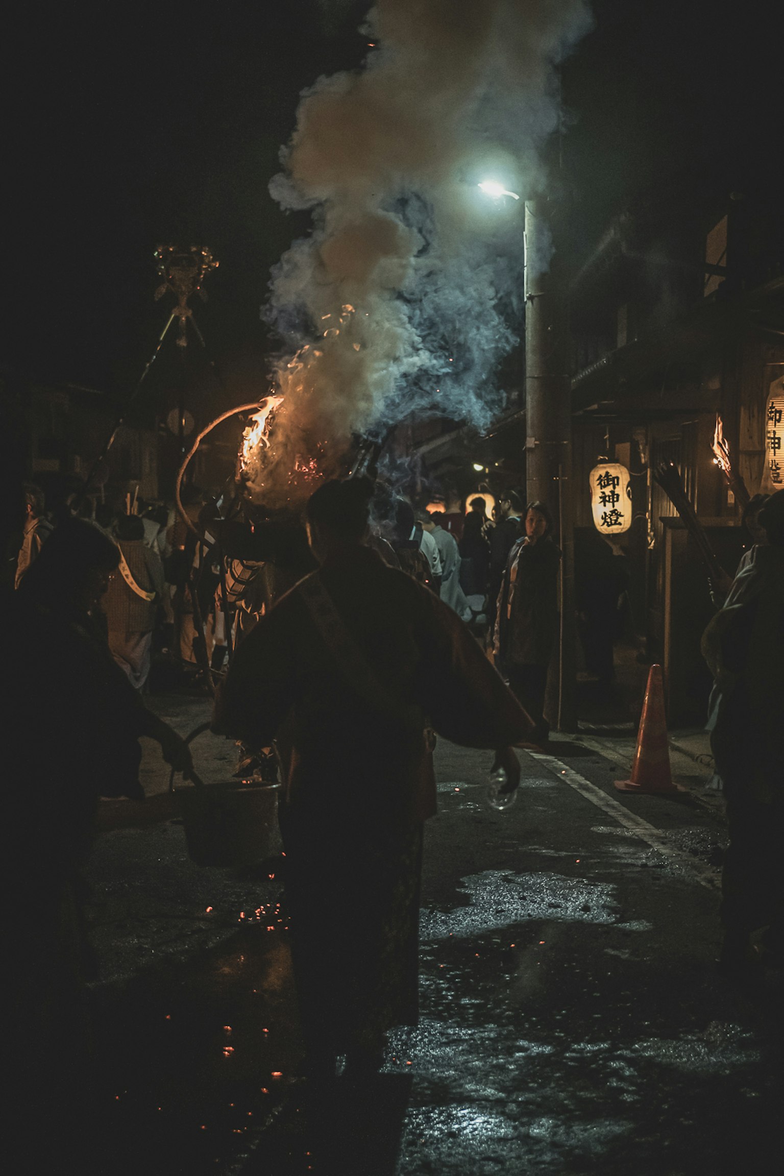 夜間祭典中持火冒煙的人們的輪廓