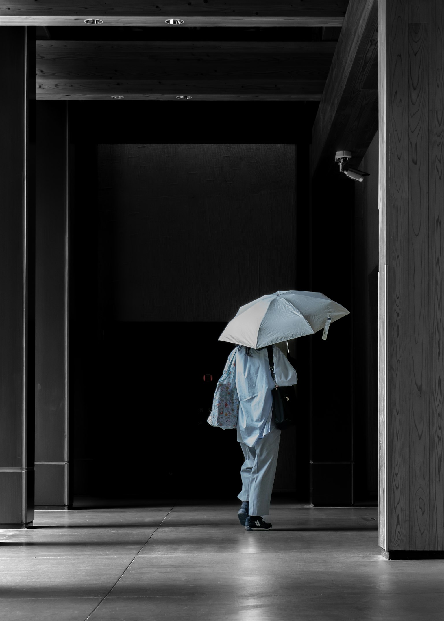 青い傘を持った人物が暗い廊下を歩いているシーン