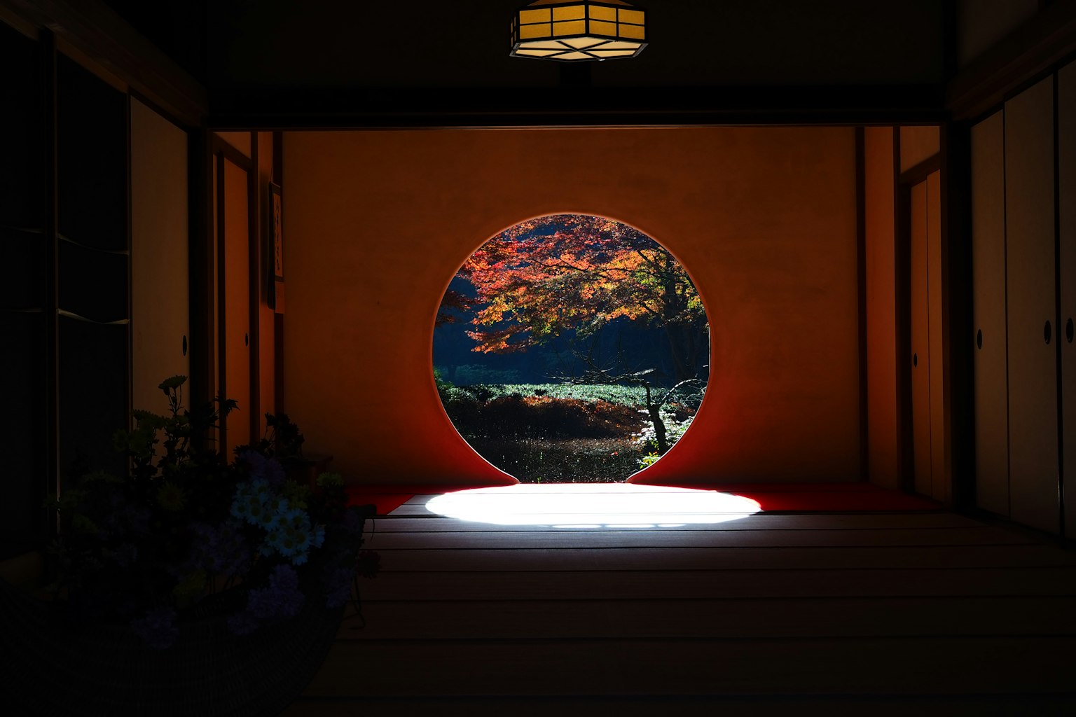 Interno di una stanza giapponese con una finestra circolare che mostra un paesaggio bellissimo