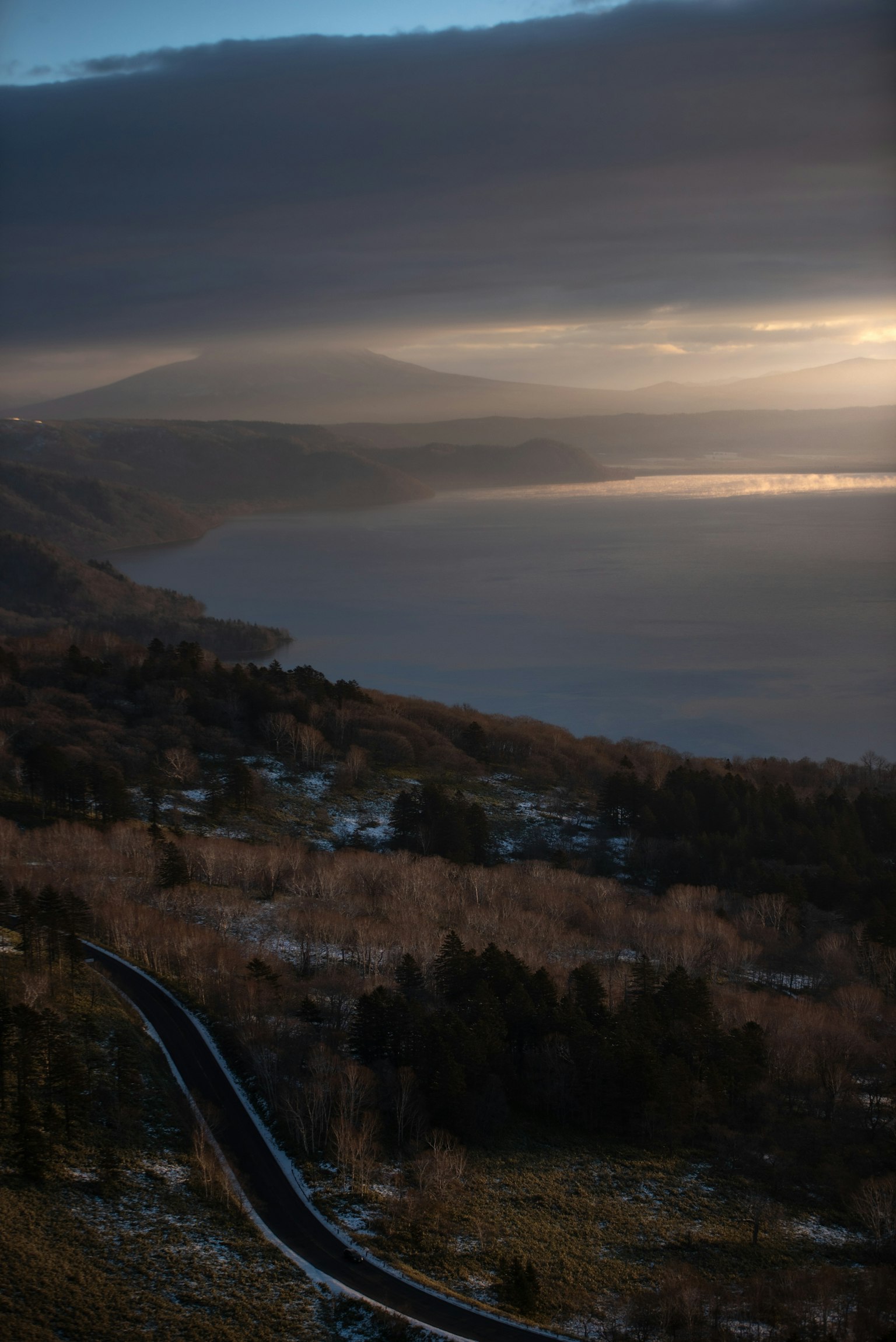 Paesaggio drammatico con una costa e montagne al tramonto