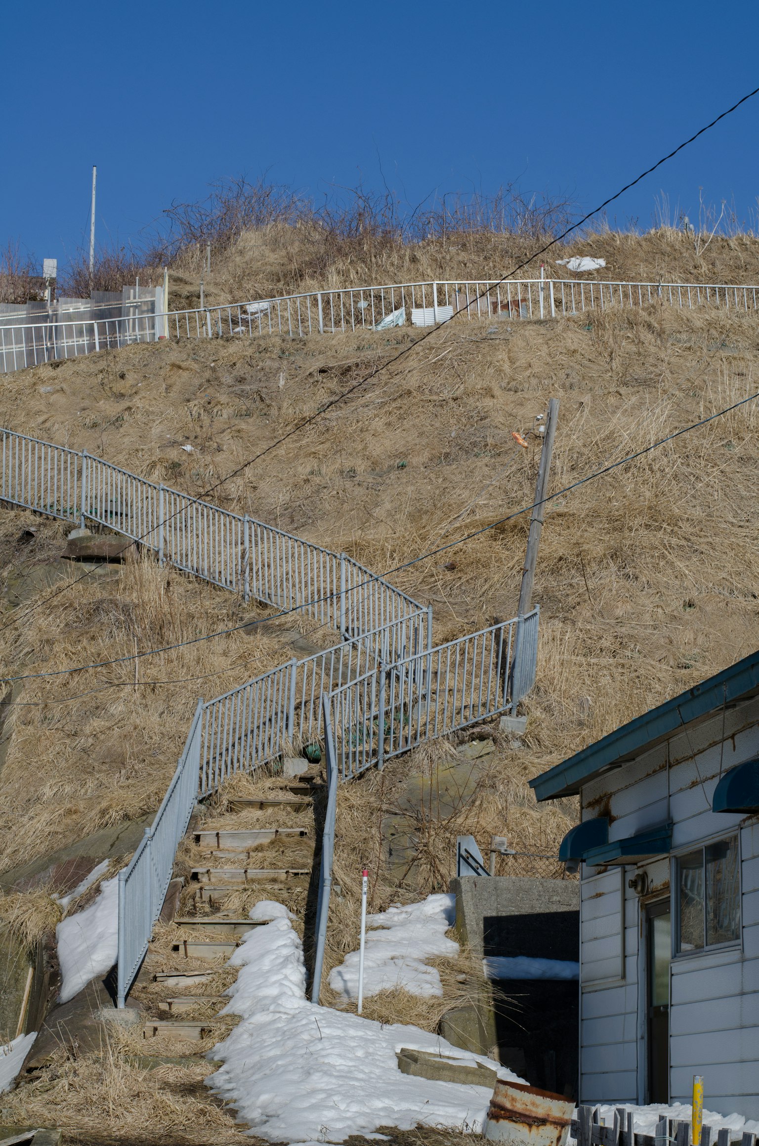 Staircase leading up a grassy hill under a clear blue sky