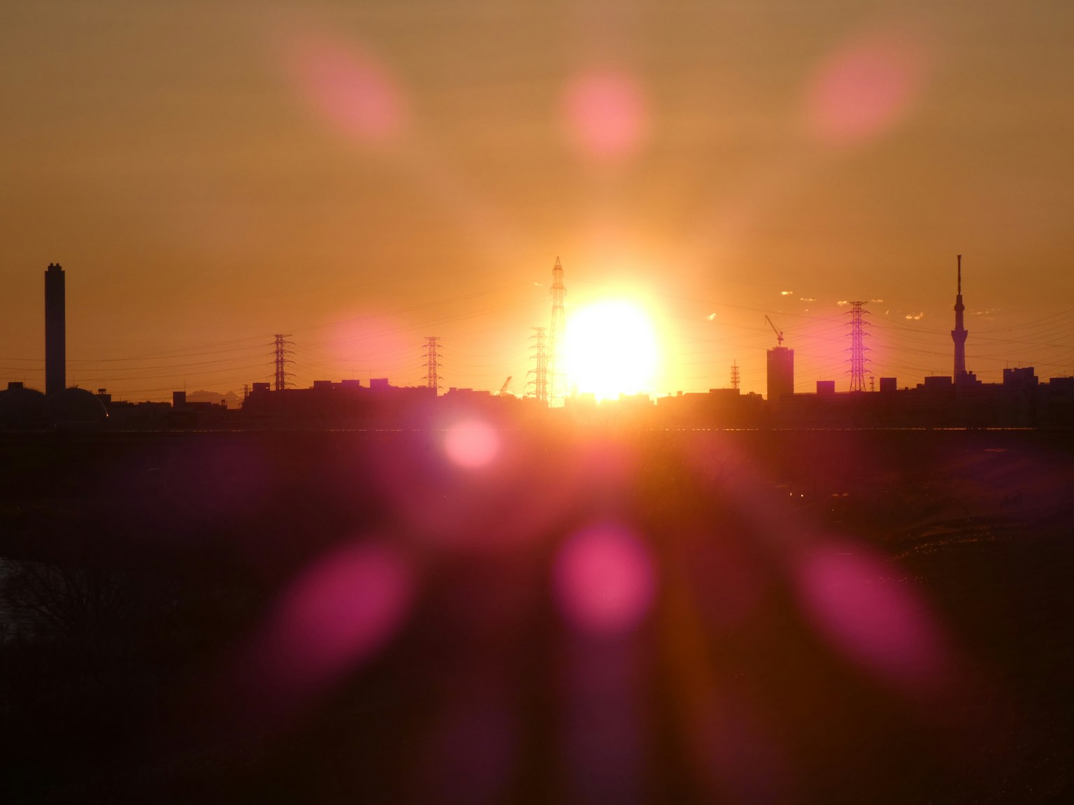 Silhouette of a city at sunset with purple light flares
