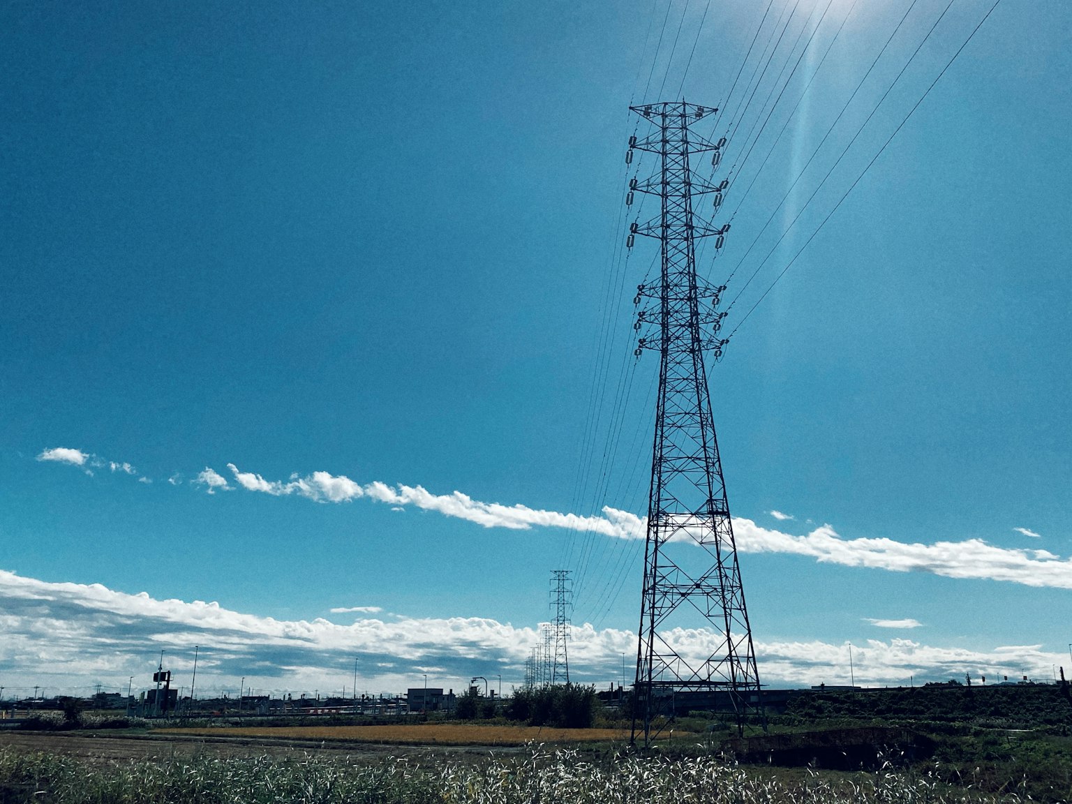 High voltage power tower under a blue sky with white clouds