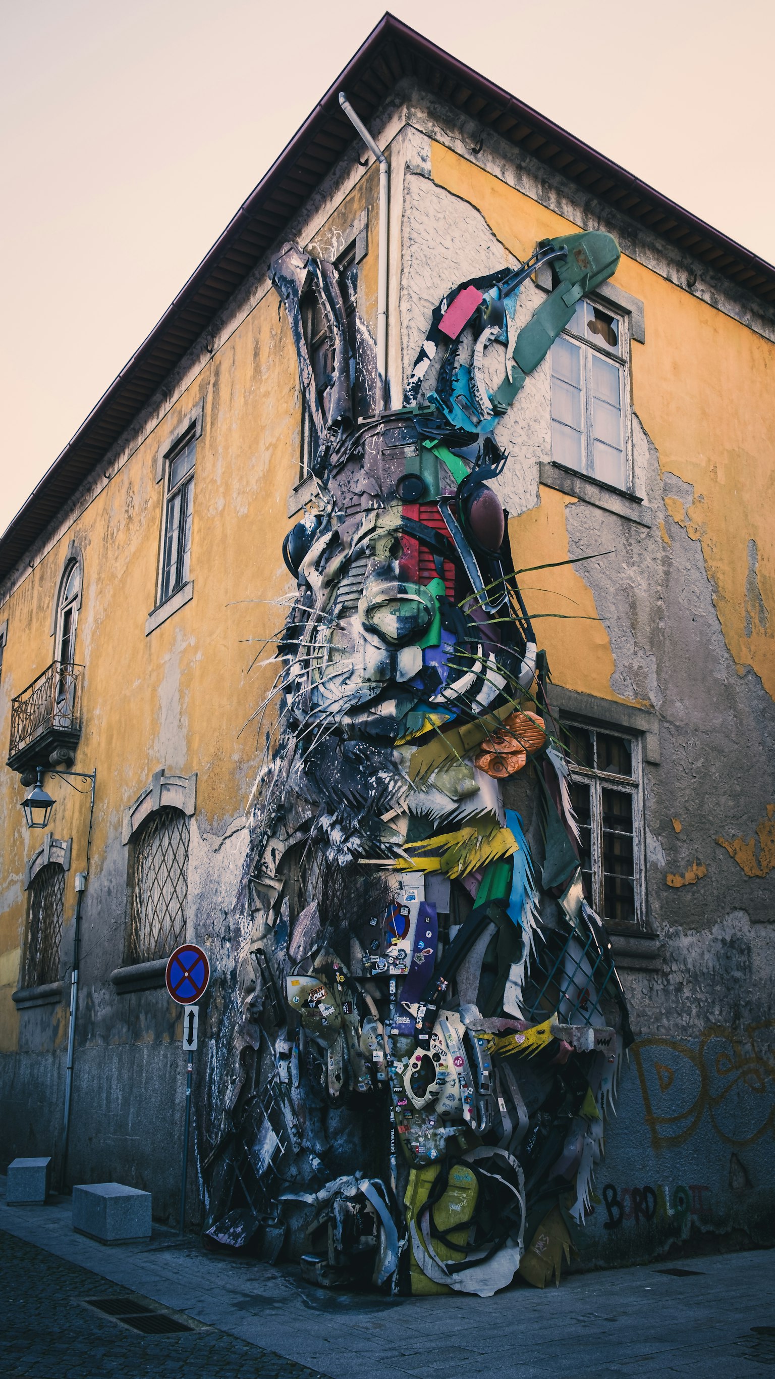 Installation artistique colorée faite de matériaux recyclés recouvrant un mur d'un vieux bâtiment