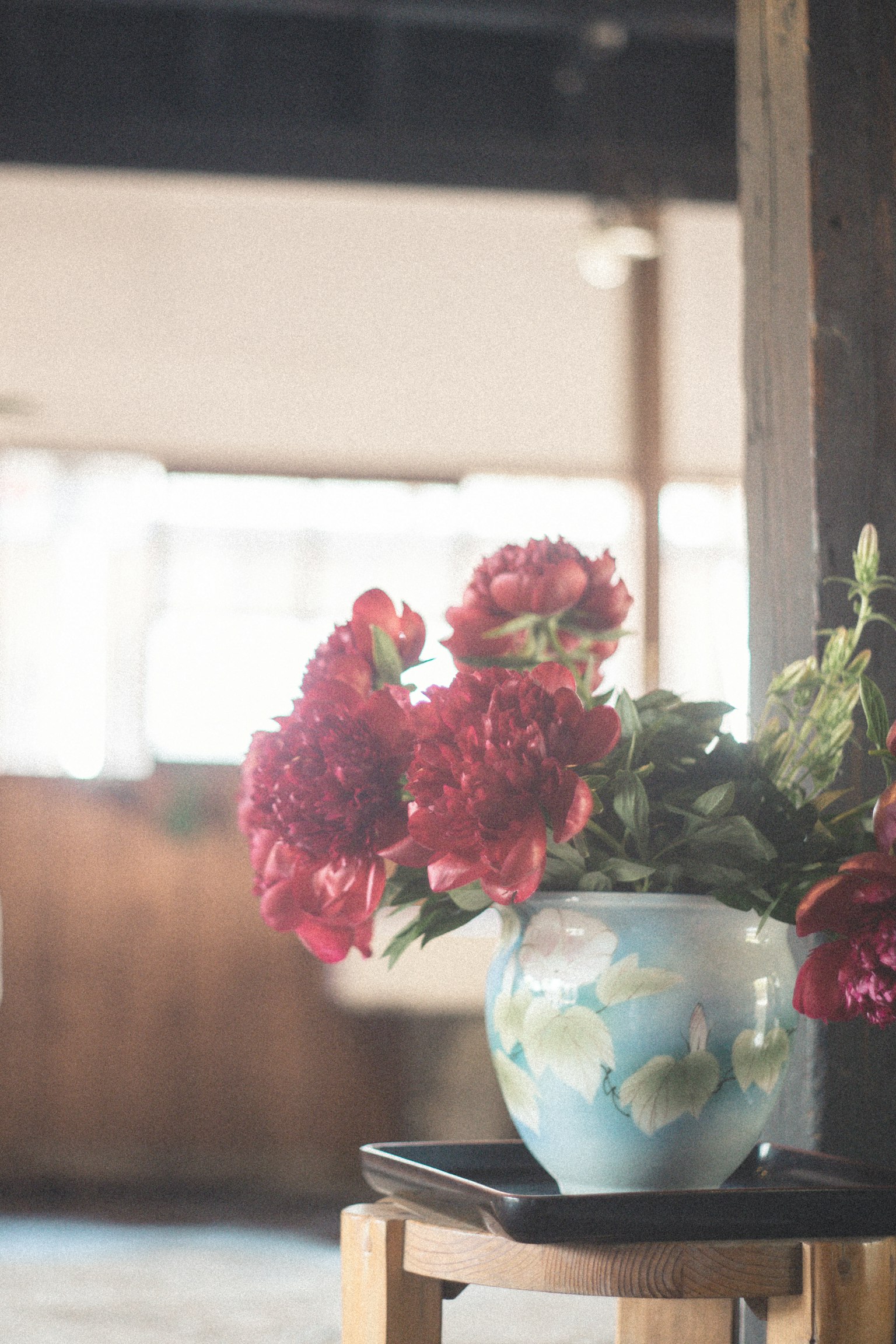 Eine blaue Vase mit roten Blumen auf einem Holztisch