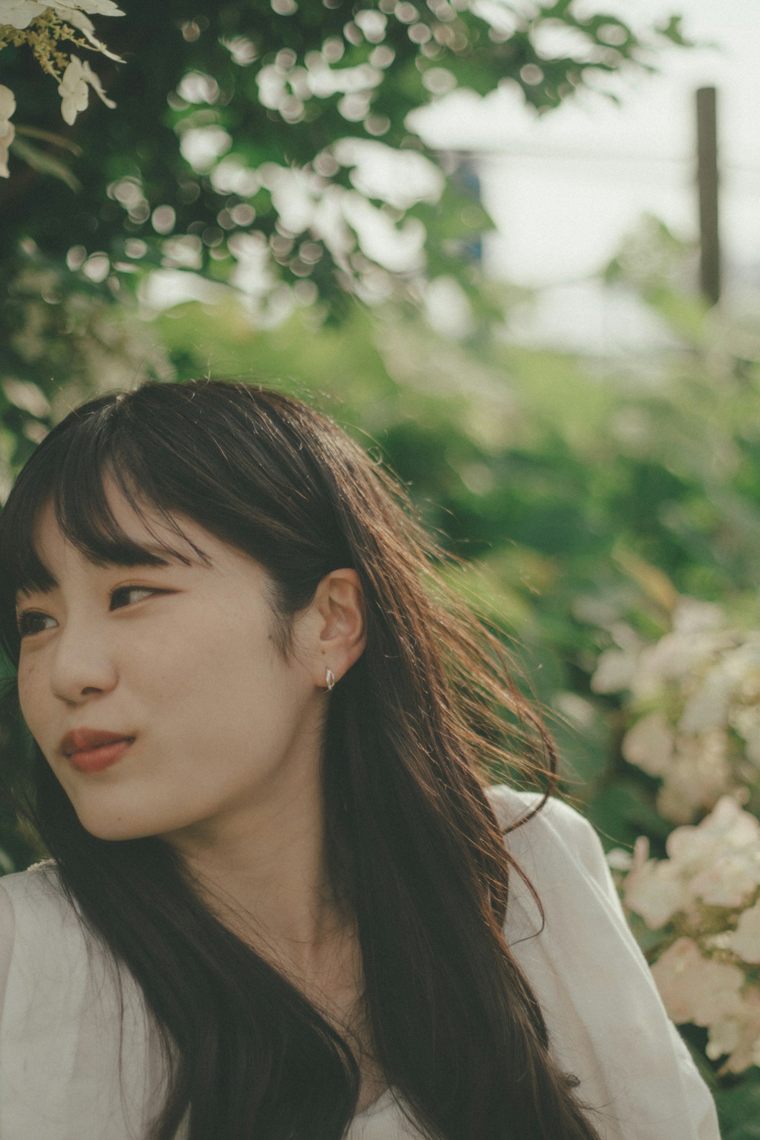 푸른 배경 앞에서 미소 짓고 있는 여성의 측면