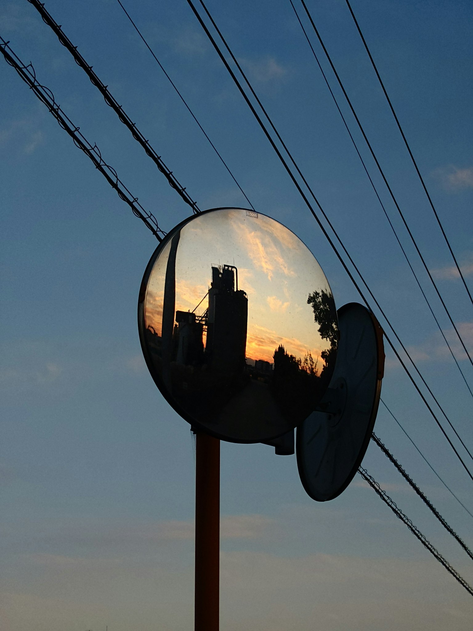 夕焼けの空を背景にした鏡に映る都市のシルエットと電線