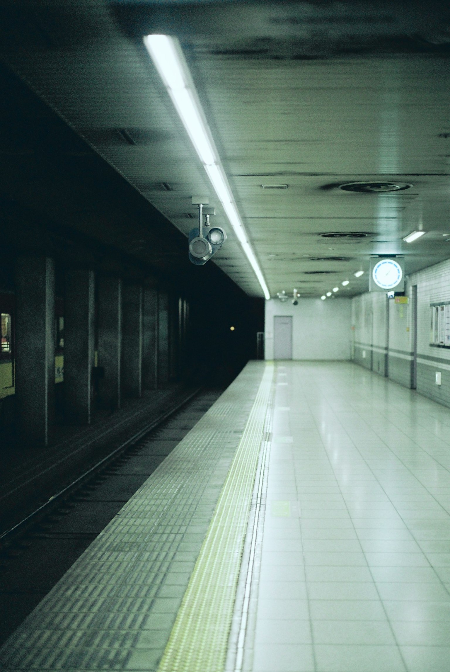 Dimly lit subway platform with clock