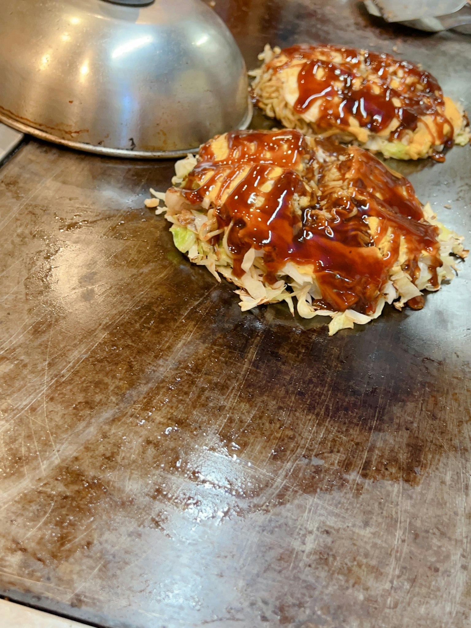 Okonomiyaki avec sauce sur une plaque de cuisson