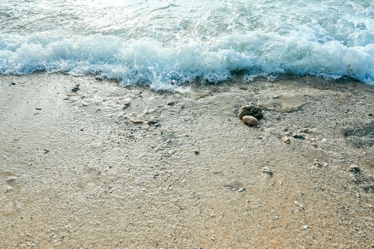 Onde che lambiscono dolcemente una spiaggia sabbiosa