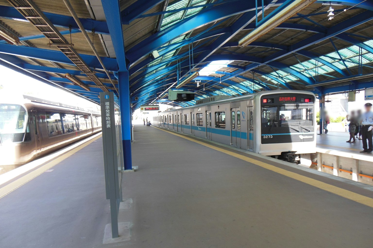 Zug auf einem Bahngleis mit blauem Dach und Menschen