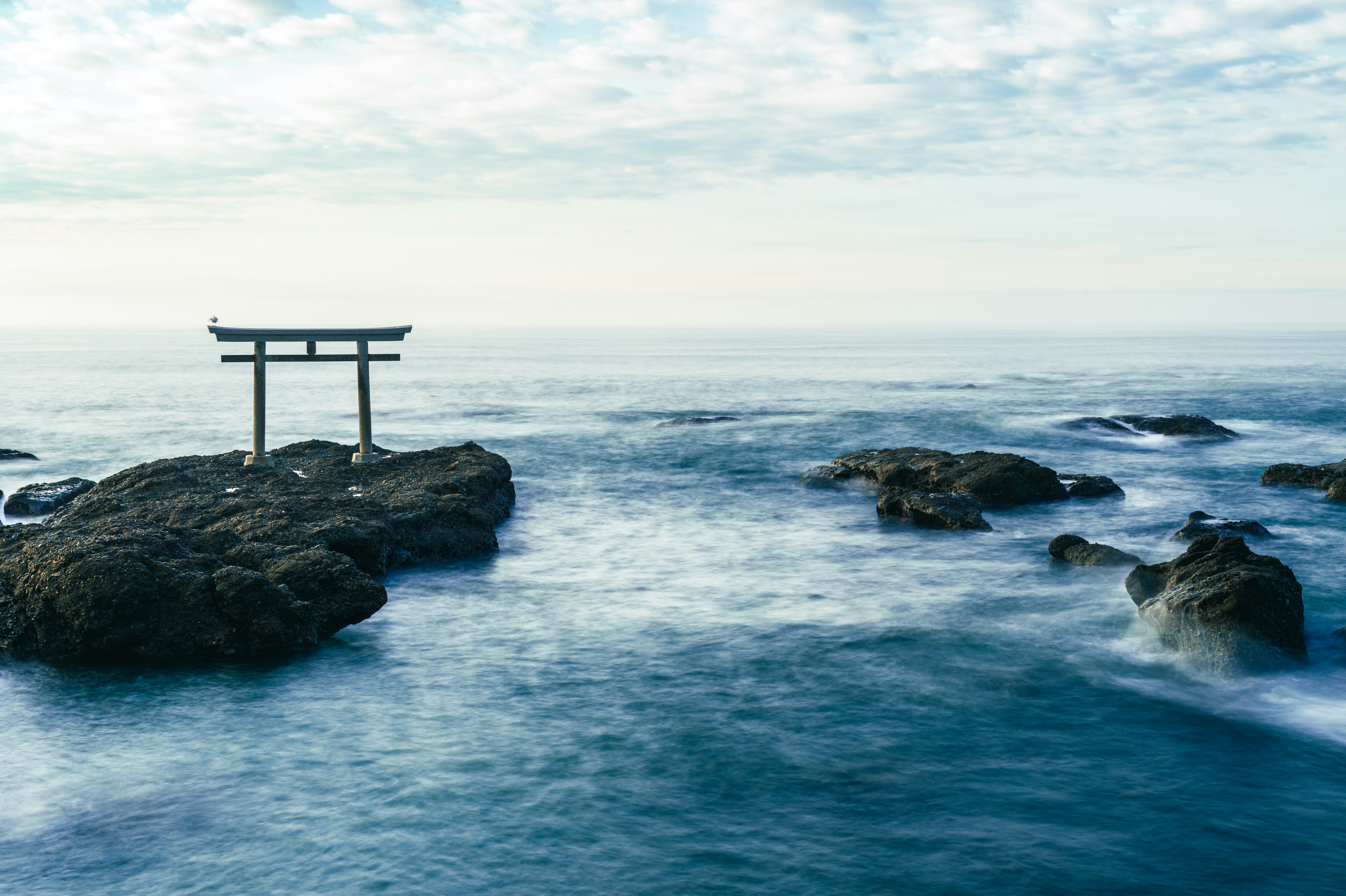 鳥居のある海辺の岩場の夜明けの風景