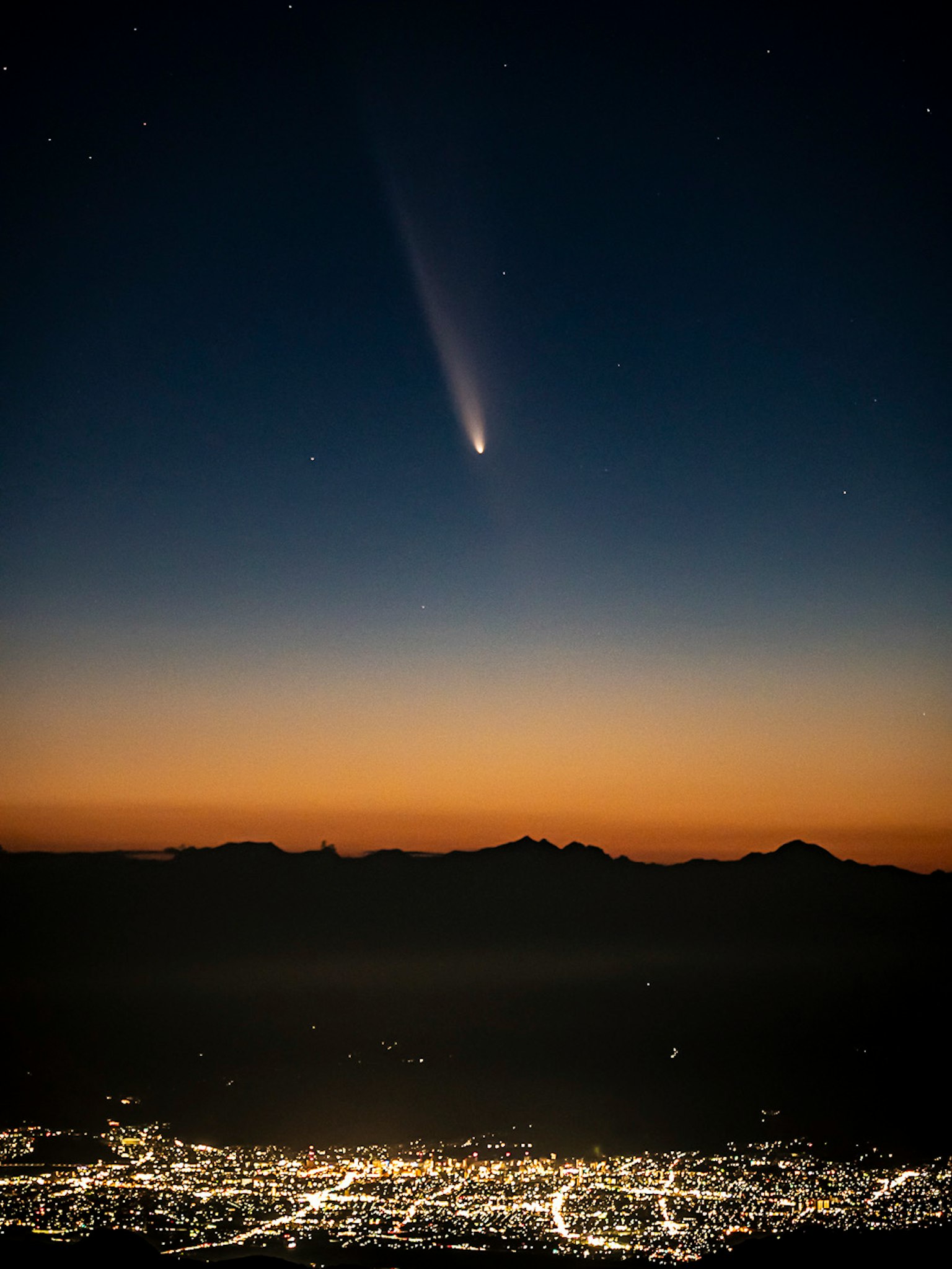Comet in the night sky above a cityscape