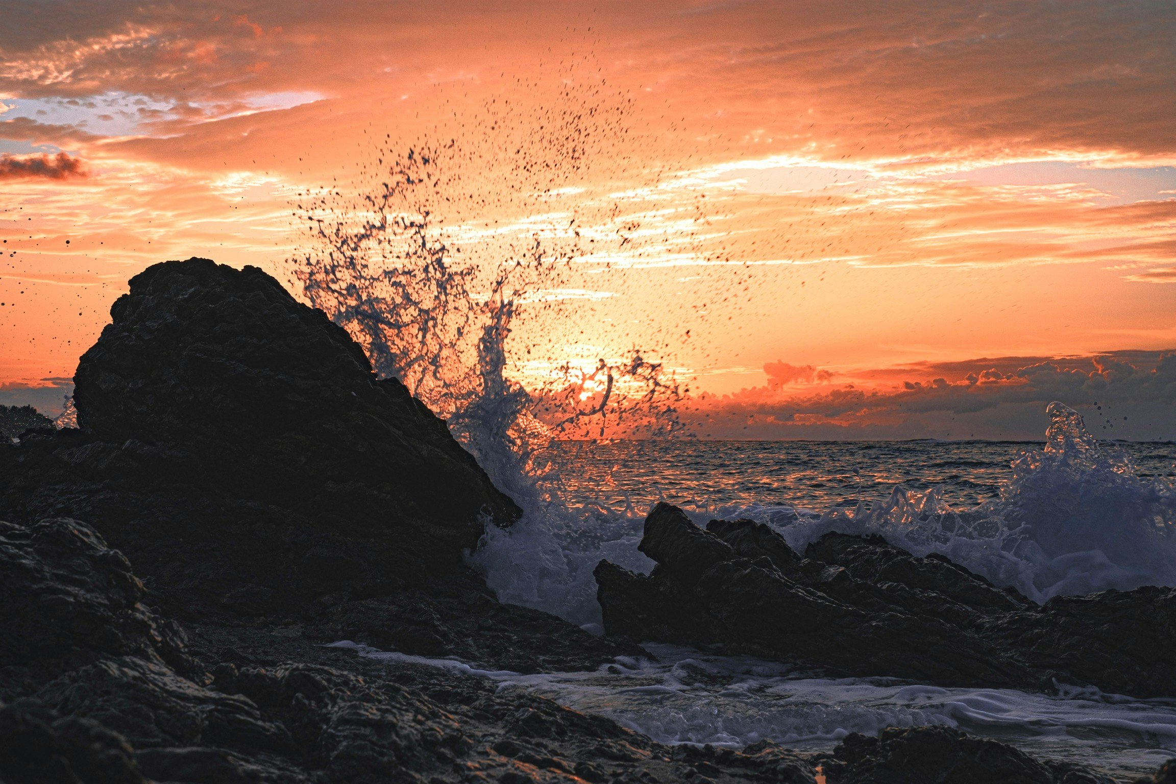 waves crashing on rocky coastline at sunset